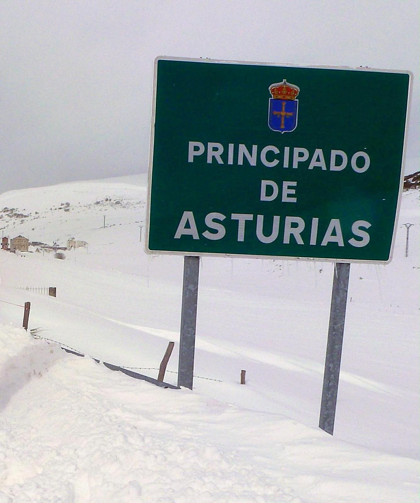 Cartel verde de Principado de Asturias junto a la carretera del puerto, todo nevado