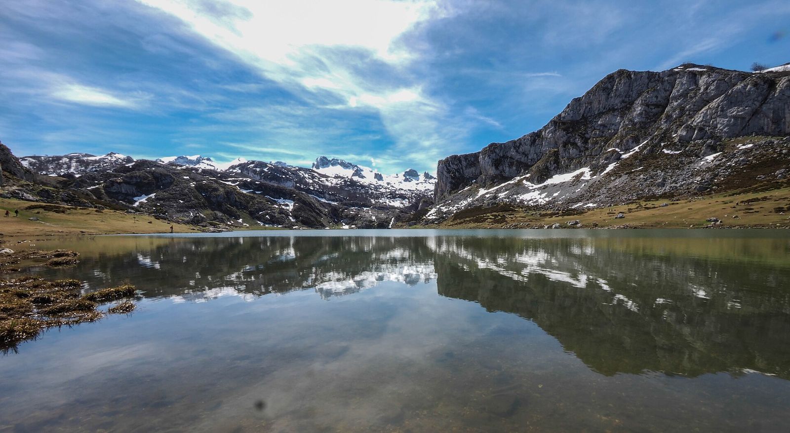El lago Ercina en calma al principio de la primavera, con las cumbres aún nevadas reflejadas en el agua