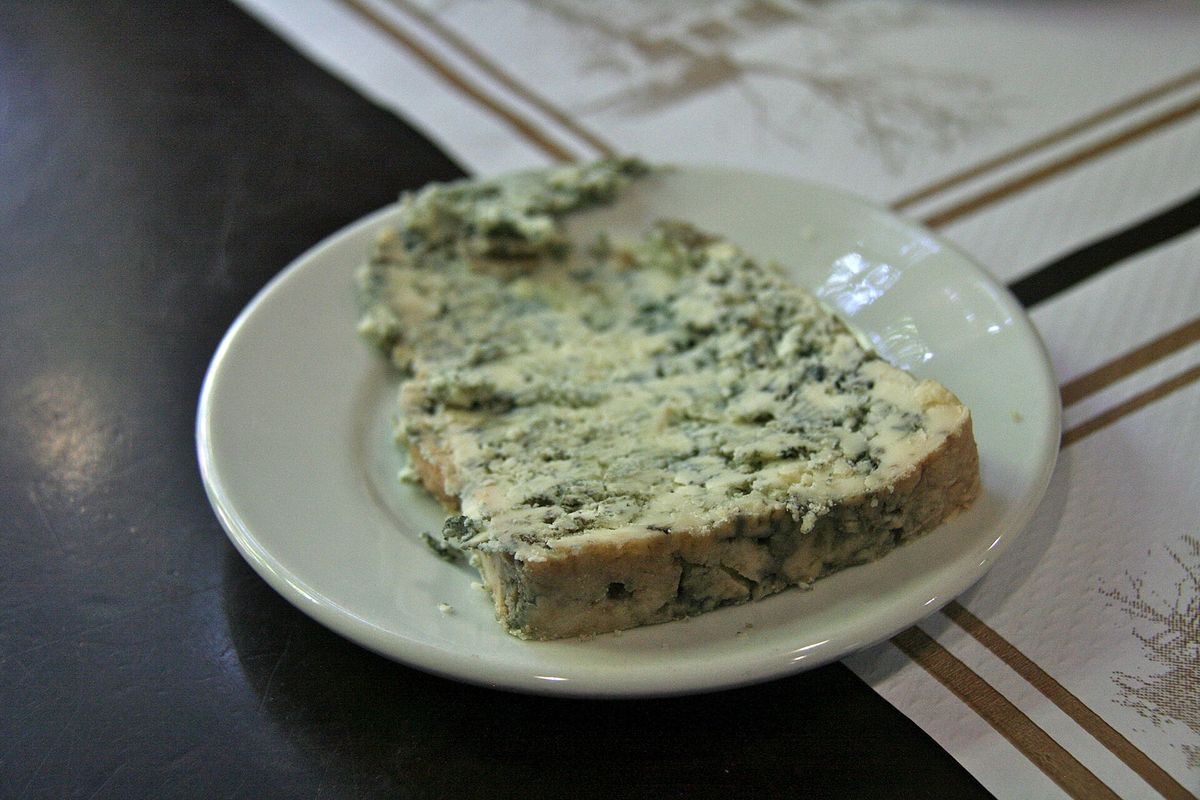 Cuña de queso de Cabrales con sus vetas azules en un plato blanco