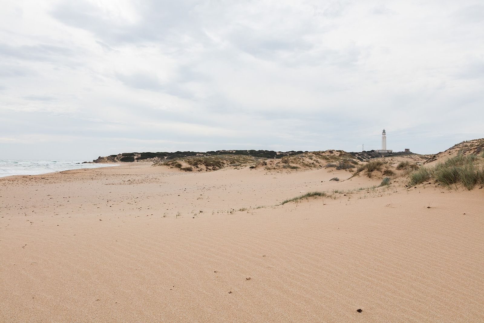 Playa de Zahora vacía en un día nublado, con las dunas y el faro de Trafalgar al fondo